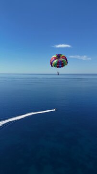 Vertical aerial view of parasailing above a turquoise sea