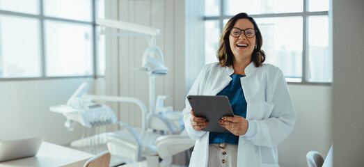 Fototapeta premium Her smile gives the dentist a warm and confident presence in the clinic