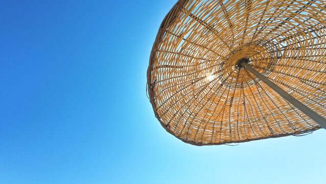 Straw beach umbrella against a blue sky background. Vacation, summer vibes, relaxed, quiet, peaceful atmosphere concept. Straw beach umbrella in Marmaris, Mugla. Copy space, blank, empty. 