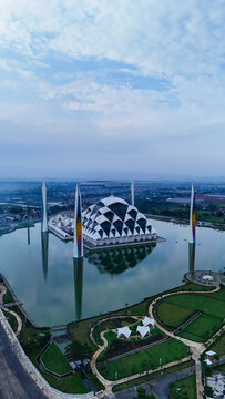 Aerial view of Al Jabbar Grand Mosque with its unique geometric dome and tall minarets surrounded by a reflective pond and landscaped gardens in Bandung, West Java, Indonesia.