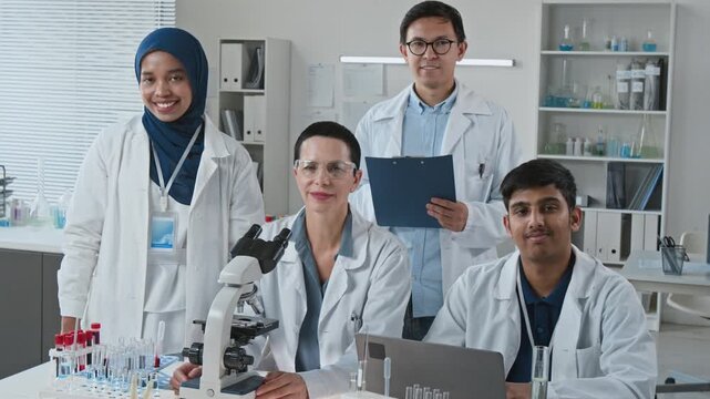 Portrait of multiethnic young adult and middle aged scientists smiling in medical laboratory. Clip enhances biotechnology advertising, clinical trial promotions, and medical team presentations