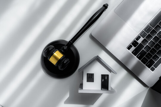 Top view of judge gavel, model house and laptop on a desk representing real estate law, online property auction, mortgage foreclosure, legal contracts, housing finance and property investment.