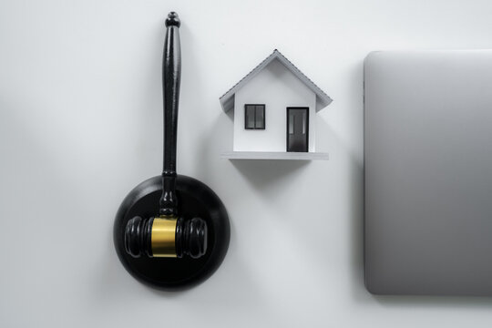judge gavel, model house and laptop represents real estate law, property auction, mortgage foreclosure, housing disputes, legal contracts and digital residential property transactions. Top view.