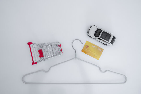 Credit card, shopping cart, car model and clothes hanger represent consumer debt, installment payments, buy now pay later, personal budgeting, retail spending and vehicle financing decisions.