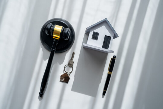 Judge gavel, house model, home key and pen symbolize property law, real estate contracts, home ownership, legal agreements, housing rights and residential property transactions.