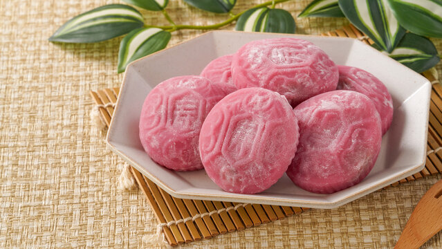 Traditional pink red turtle rice cake on woven grass mat background.