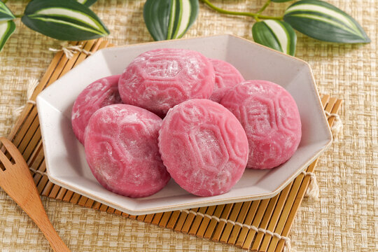 Traditional pink red turtle rice cake on woven grass mat background.