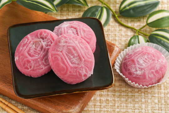 Traditional pink red turtle rice cake on woven grass mat background.