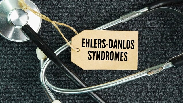 Stethoscope and paper tag with the words Ehlers-Danlos syndromes EDS are a group of 13 inherited connective tissue disorders that weaken support structures in the skin, joints, blood vessels, and inte