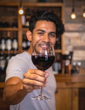  Man holding glass of red wine at wine bar 