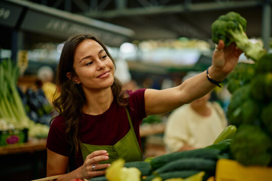 Woman buying fresh broccoli at local market