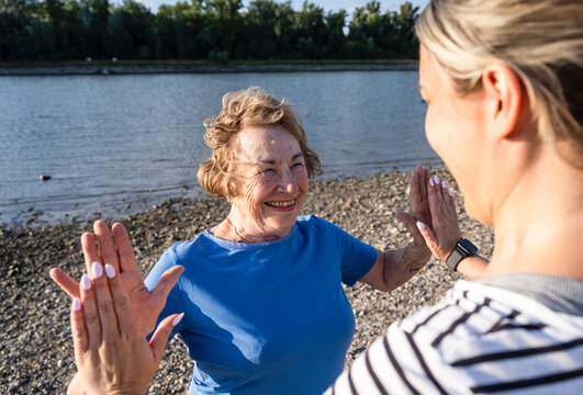 Senior woman and caregiver give high five by the river
