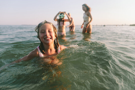 Happy girl swimming in the sea with her family in the background
