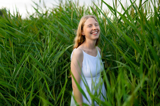 A radiant young woman enjoys summer nature in tall green reeds