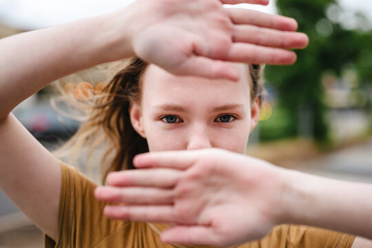 Woman frames her eyes with hands outdoors