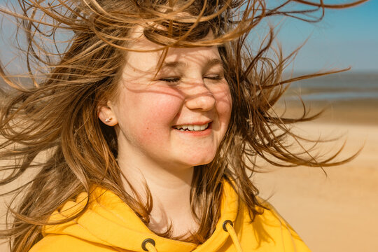 Smiling teenage girl enjoys the wind at the beach in Germany