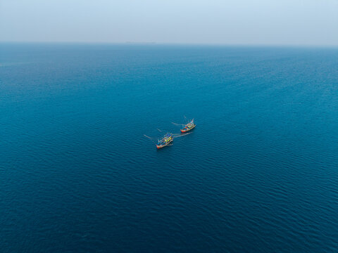 Aerial view of two fishing vessels known as kapal pukat floating on the calm deep blue sea in Karimunjawa, Central Java, Indonesia.