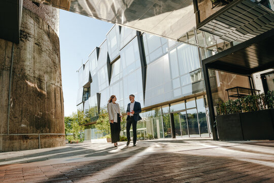 A businessman and a businesswoman discuss work outside an office