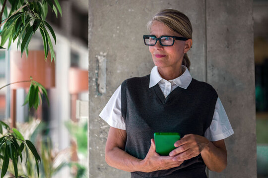 Confident businesswoman holds a smartphone in a modern office