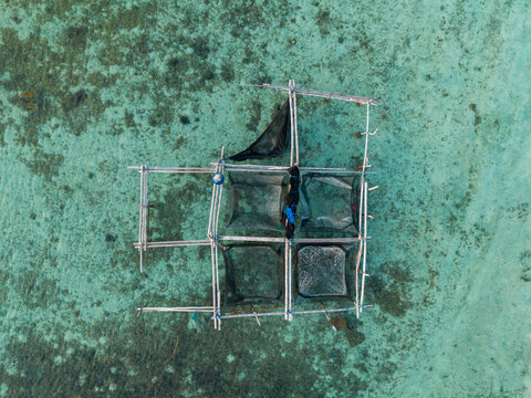 Aerial view of a traditional wooden fish cage floating in the clear turquoise waters of Karimunjawa, Central Java, Indonesia.