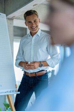 Smiling businessman presenting on flipchart to woman in office