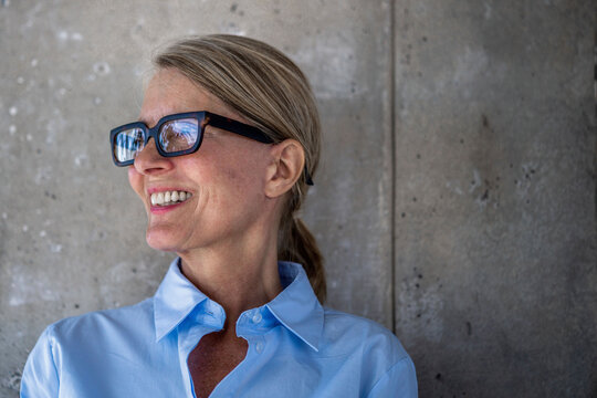 Confident businesswoman shows a bright smile by a concrete wall