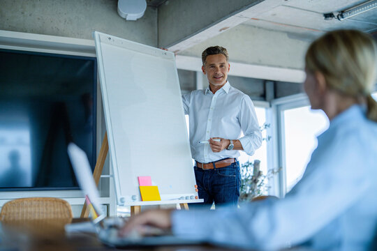 Businessman presents vision on flipchart to colleague in office