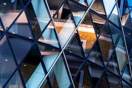Layered modern architecture in London England with a geometric diamond glass facade framework reflections and interiors across the glass facade