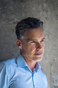 Thoughtful businessman contemplates vision near concrete wall