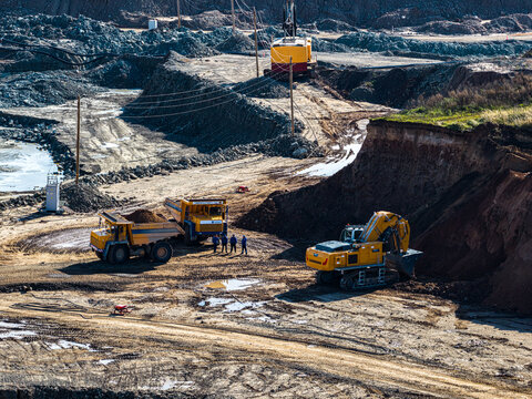 Aerial view of the Dolomitas mining quarry featuring heavy excavators and dump trucks with workers standing on the excavated ground in Petrasiunai, Siauliu apskritis, Lithuania.