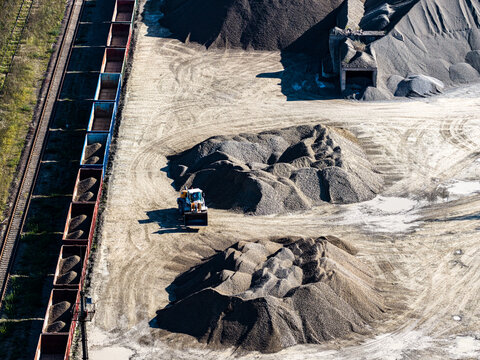Aerial view of the Dolomitas gravel quarry with a loader working near large piles of crushed stone next to a freight train with open wagons in Petrasiunai, Siauliu apskritis, Lithuania.