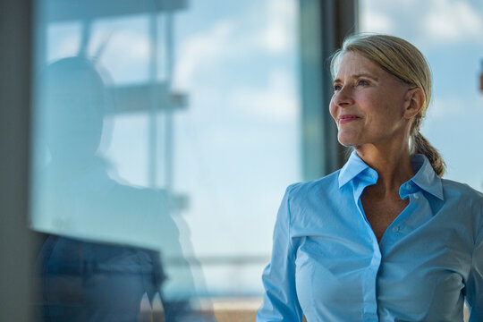 A confident businesswoman looks out a window planning future success