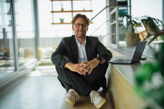 Smiling businessman wearing a suit contemplates success in the office