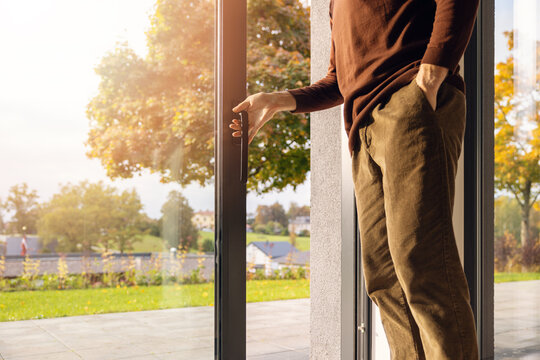 Man opening large aluminum sliding glass patio door to a backyard garden