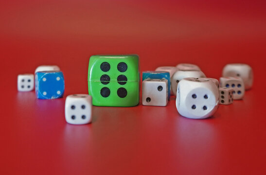 Dice on a red background. Large green cube in the center, shallow depth of field.