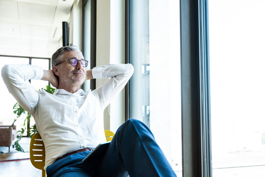 Smiling businessman takes a break by the office window