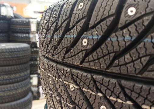 Studded winter tires close-up. Two stacks of tires with pronounced tread, a blurred background of an auto supply store.