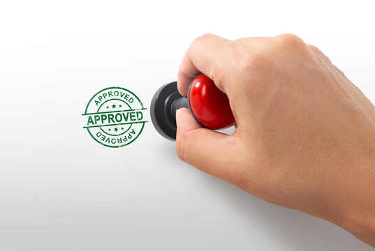 Hand stamping green round approved rubber stamp seal isolated on white background close up