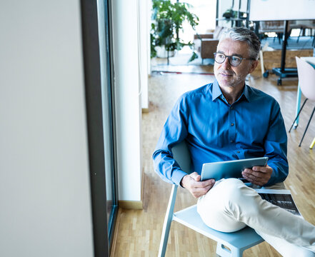Smiling businessman holds a tablet in the modern office