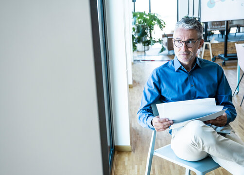 Businessman holds document and tablet in the office