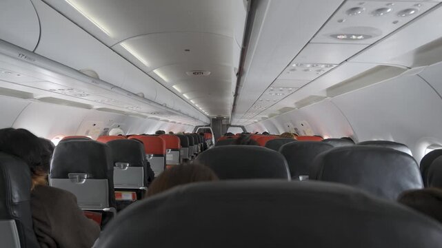 view inside onboard airplane full with passenger sitting while airplane climbing , A realistic view inside the airplane cabin showing many passengers seated, with a warm color tone