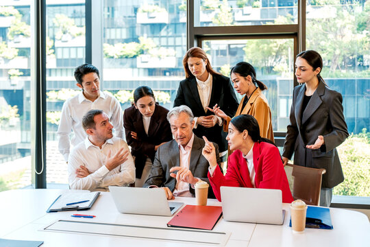 Diverse business team holds an office meeting around laptops, discussing strategy, teamwork, leadership, collaboration, planning, communication and corporate decisions.