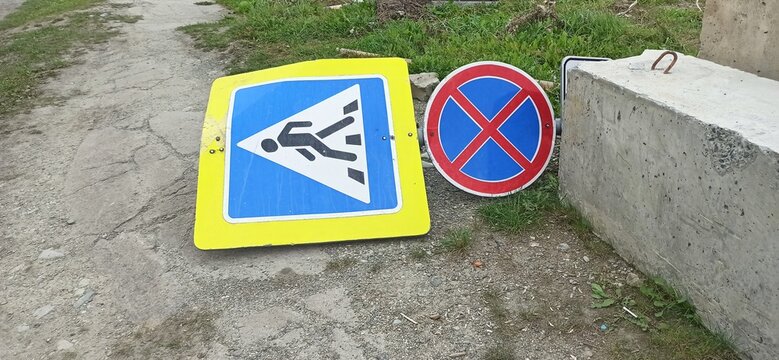 Road signs lying on the ground. The "Pedestrian crossing" sign and the "Parking prohibited" sign are knocked down by a car and lying on the ground
​
​