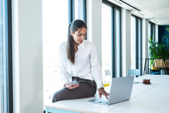 Businesswoman uses a notebook and smartphone in the modern office