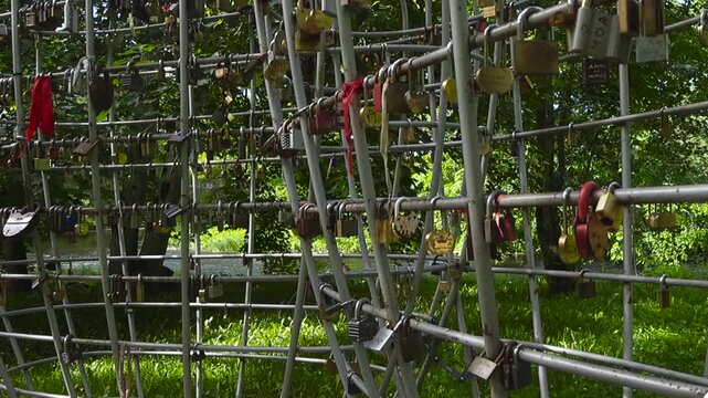 Colorful love padlocks left by newlyweds and couples hanging on a unique metal structure in a green park, symbolizing eternal love, commitment, and unbreakable bonds in a beautiful tradition