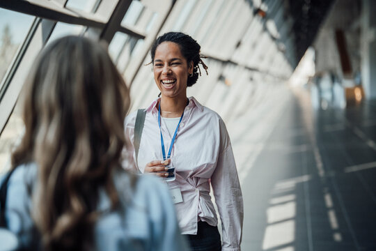Two businesswomen talk and laugh at a trade fair corridor