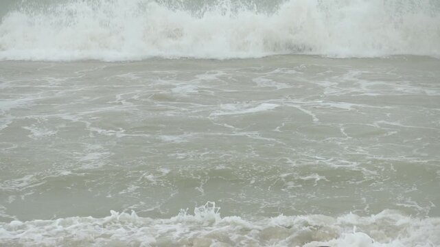 landscape view of heavy wave oceanic foam is coming to the beach while in storming heavy raining weather. aerial footage landscape and water waves with nobody. vacation outdoor landscape texture
