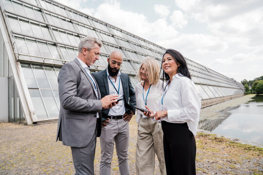 Businesspeople converse outdoors during a trade fair break