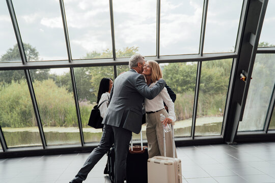 Businessman greets businesswoman at airport terminal