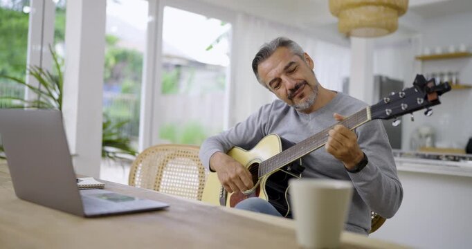 Portrait of elderly caucasian man musician as hobby. Senior male blogger teach guitar playing at living room. Handsome mature old man in casual clothes is smiling while playing guitar at home.